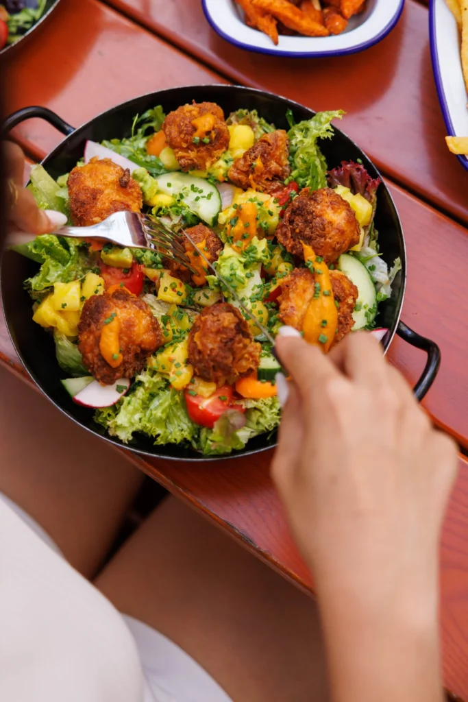 Fresh salad with crispy fried vegan bites served in a pan at Let's Be Frank Vienna
