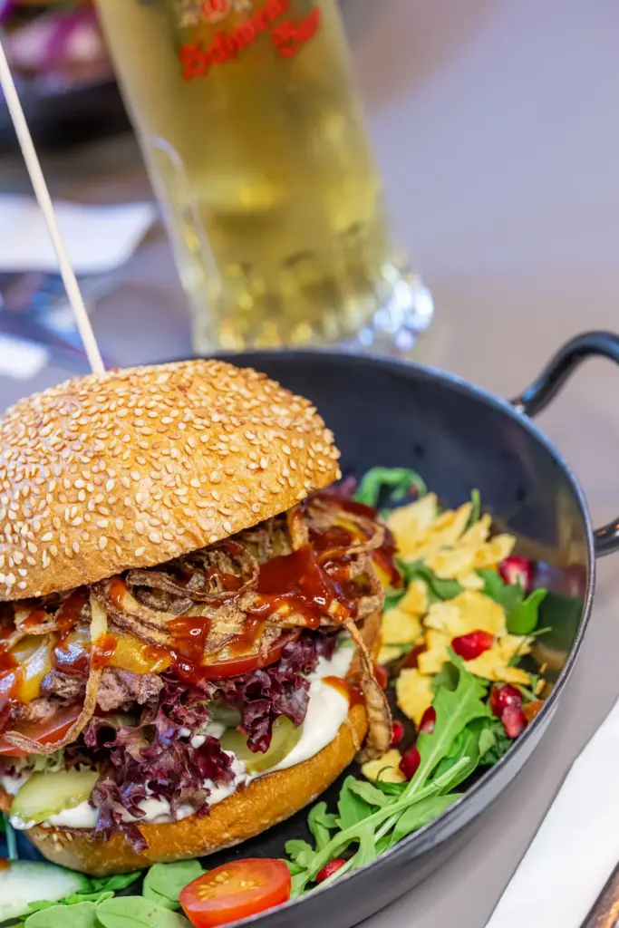Burger served in a pan with fresh salad at Let's Be Frank Vienna