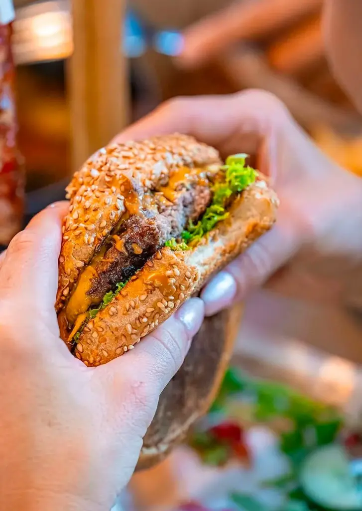 Close-up of a hand-held burger at Let's Be Frank Vienna